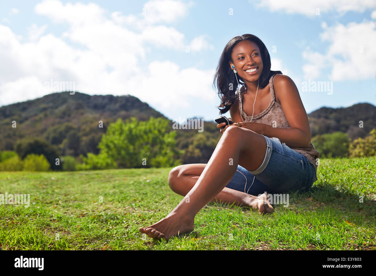 Young woman sitting on grassy hill Banque D'Images
