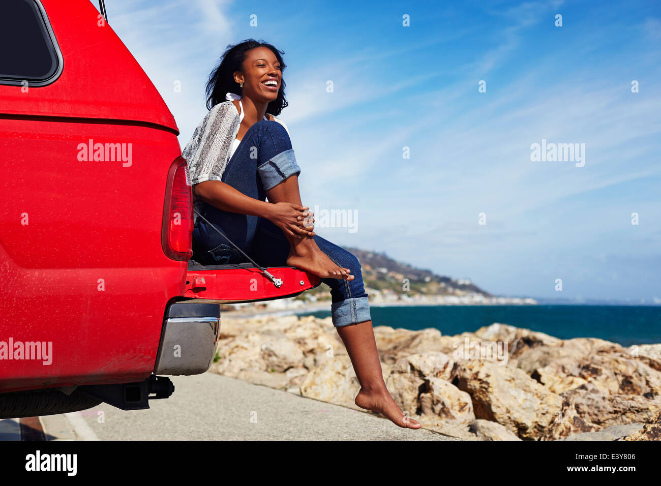 Jeune femme assise sur un capot de voiture, Malibu, California, USA Banque D'Images