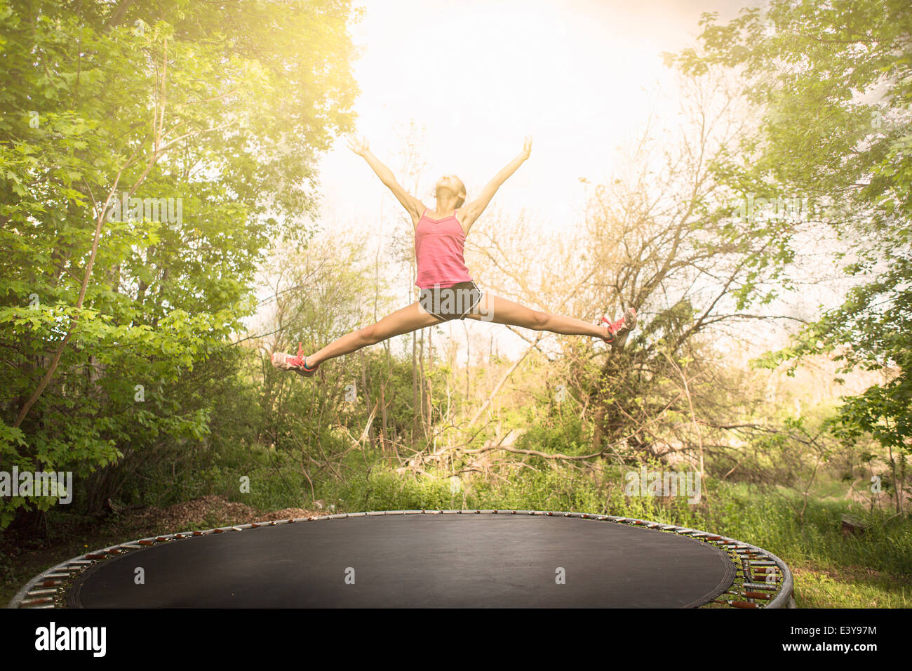 Teenage girl doing star saut sur trampoline, à l'extérieur Banque D'Images