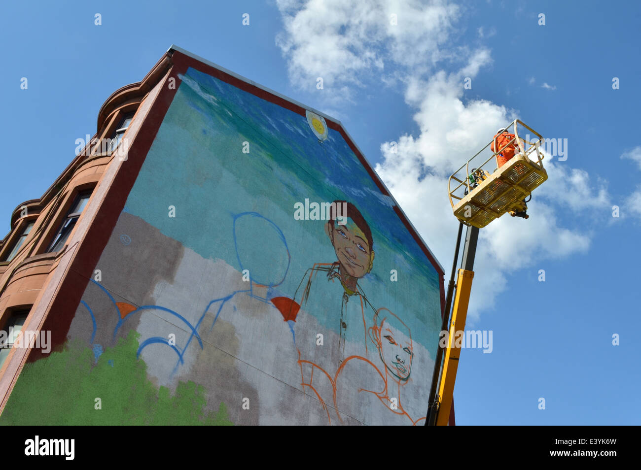 Artiste Graffiti au travail, peindre un mur pignon sur la route Maryhill Banque D'Images