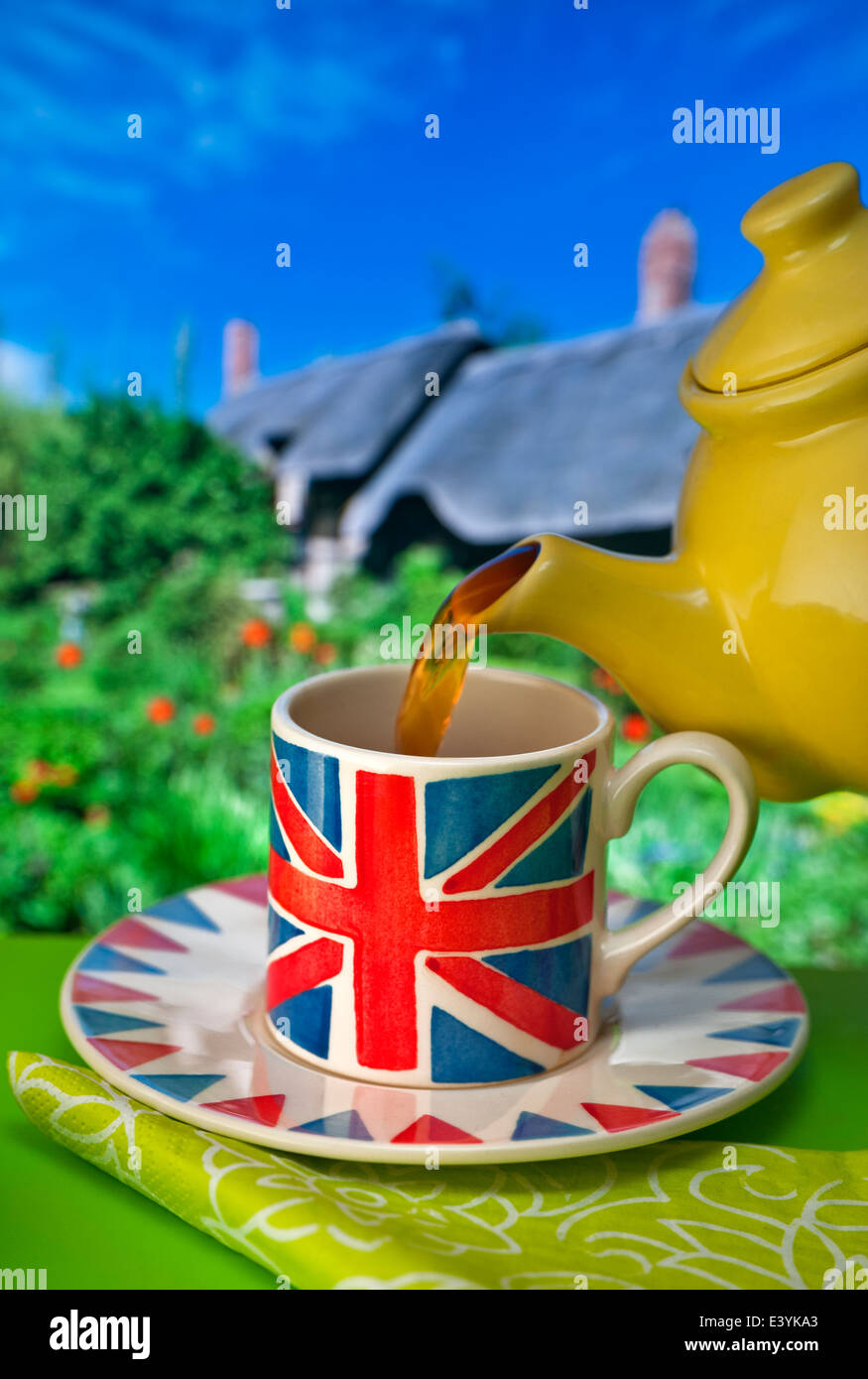 Tasse à thème Union Jack avec thé anglais, théière de chine jaune, thé avec un cottage et un jardin de chaume typique en arrière-plan au Royaume-Uni Banque D'Images