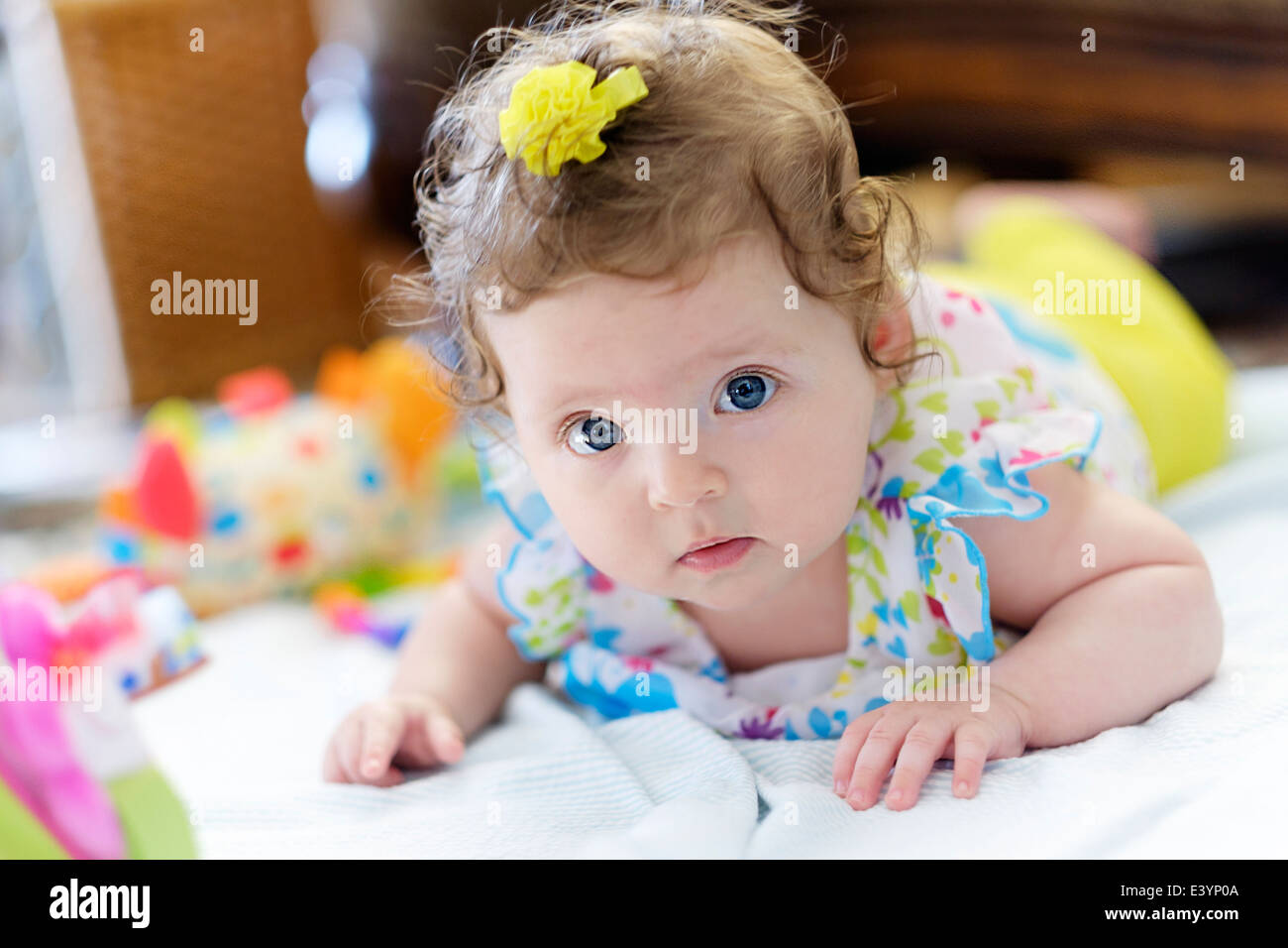 Un enfant de race blanche de trois mois allongé sur son ventre entouré par les jouets. Banque D'Images