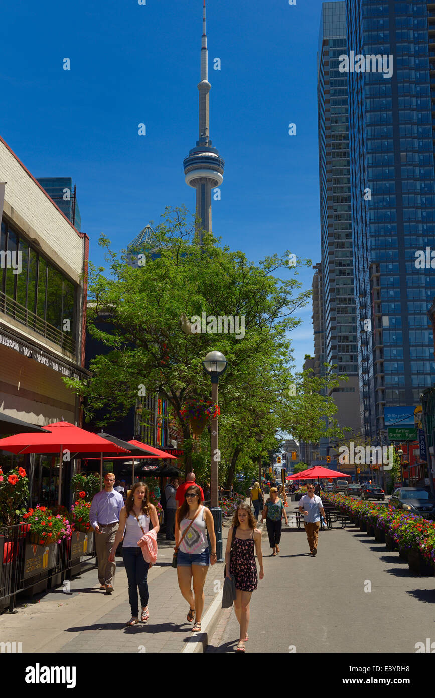 Les piétons circulant sur la rue John Toronto avec des cafés et de la tour CN et de condos de grande hauteur Banque D'Images