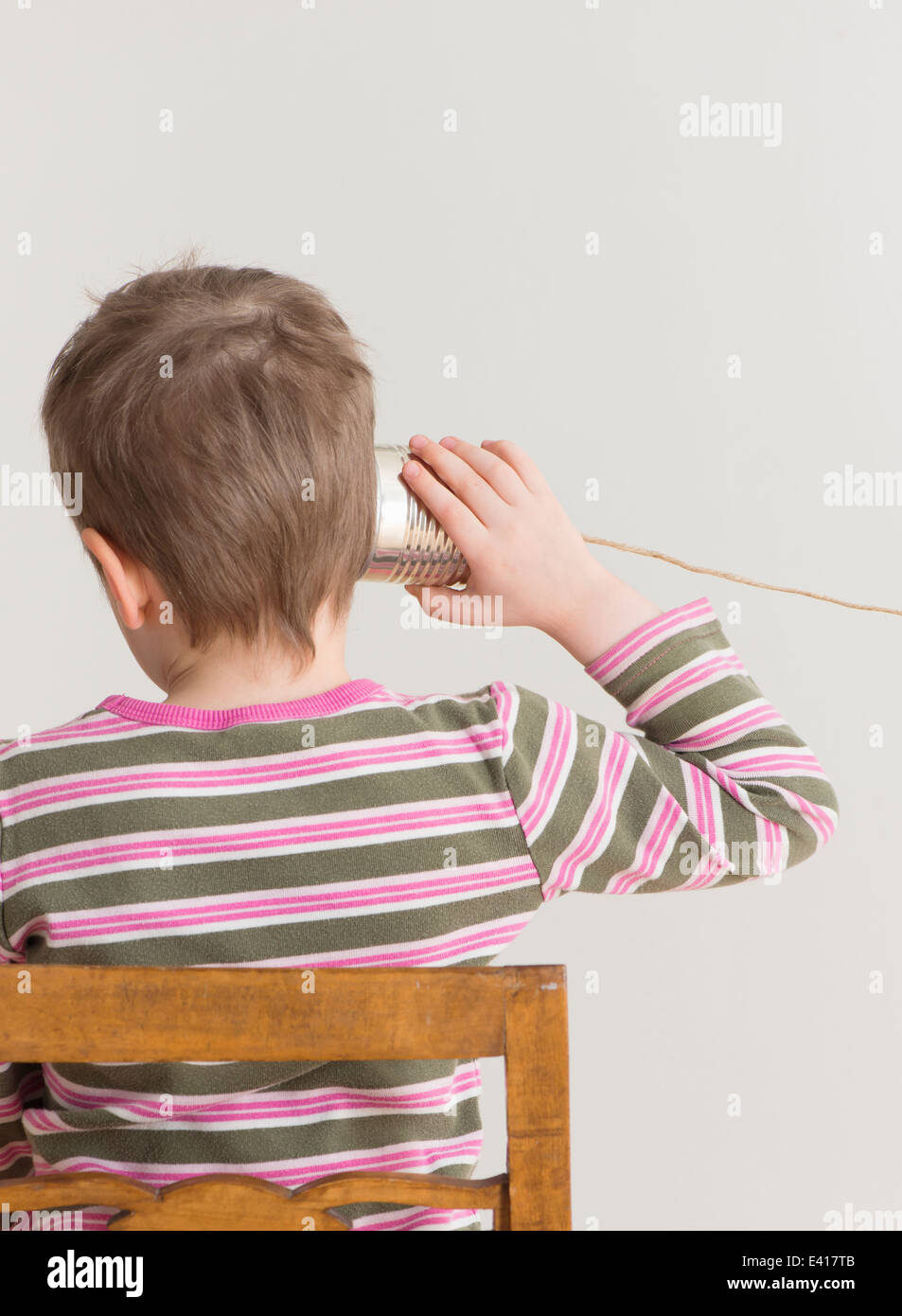 Peu d'écoute de l'enfant avec de l'étain peut téléphone. Image conceptuelle d'un jeu d'enfant et la communication. Banque D'Images