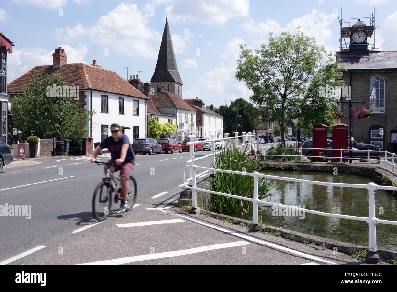 Un cycliste sur la rue principale à Stockbridge, Hampshire, Royaume-Uni. Banque D'Images
