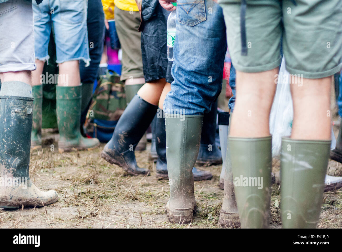 Festivaliers profitez d'un groupe à l'étape de la pyramide à Glastonbury Festival 2014, portant ses bottes dans la boue Banque D'Images