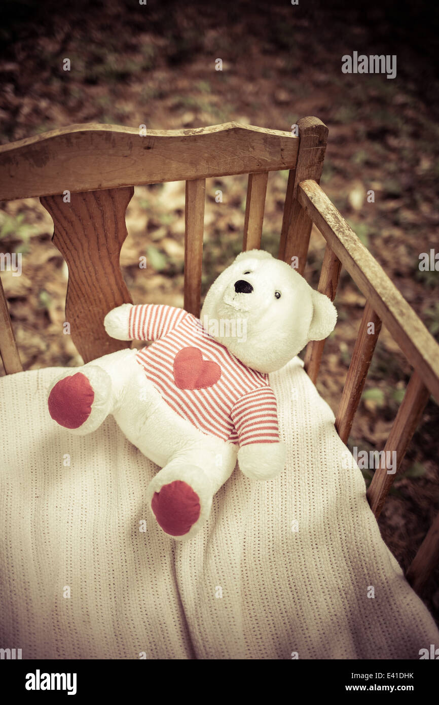 Un ours en peluche abandonné dans un lit bébé. Banque D'Images