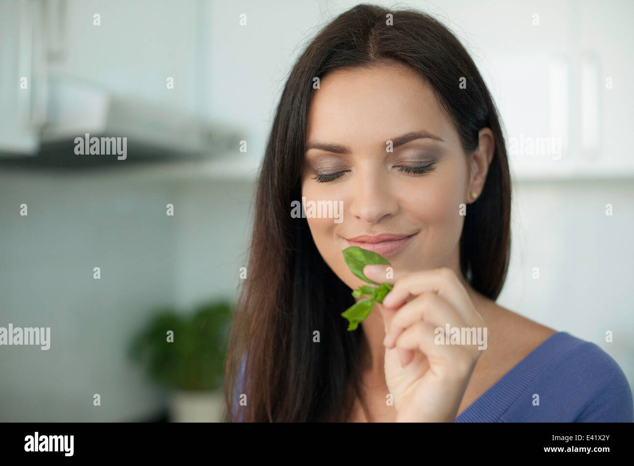 Portrait of young woman smelling basil Banque D'Images