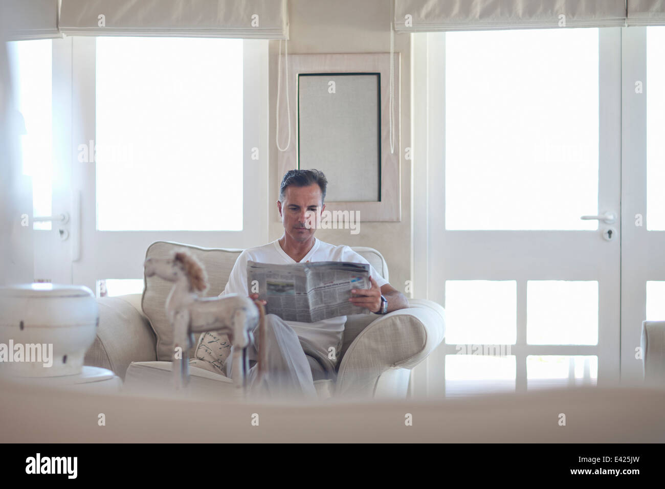 Man reading newspaper in salon Banque D'Images