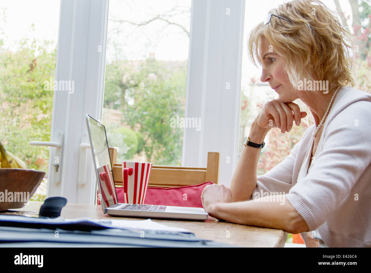 Mature Woman using laptop in kitchen Banque D'Images