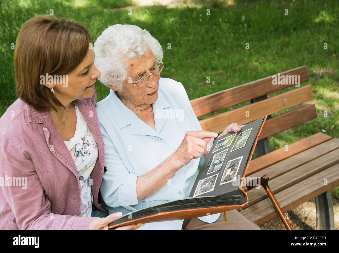 Senior woman sitting on park bench avec sa petite-fille, à la recherche de vieille photo album Banque D'Images