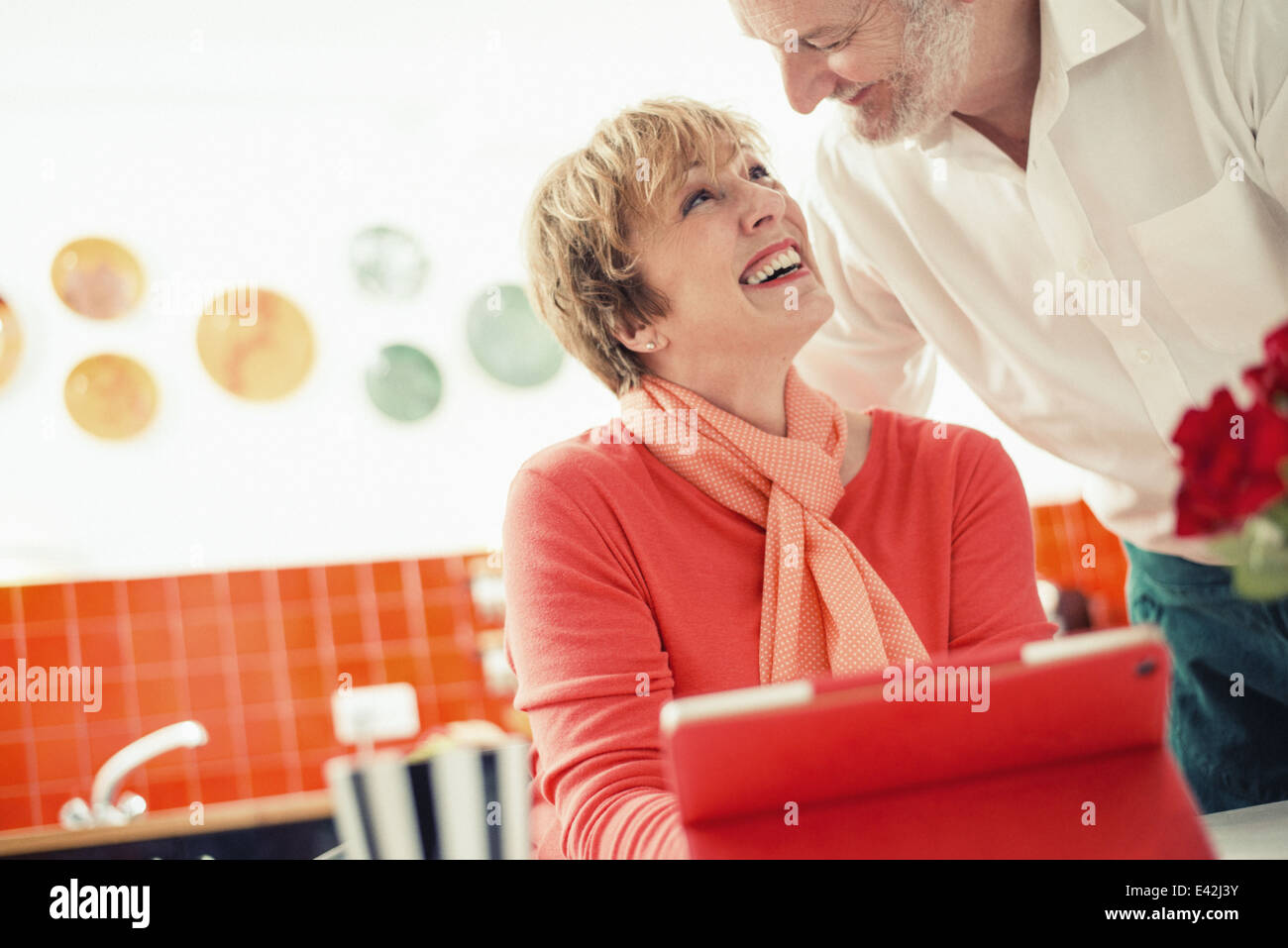 Couple in kitchen, woman with digital tablet Banque D'Images