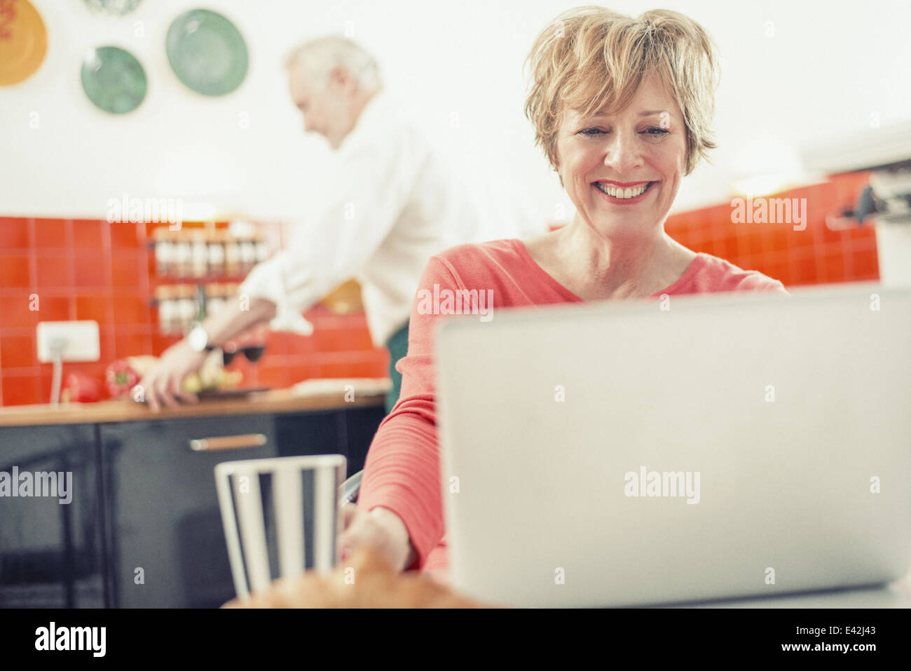 Mature Woman using laptop in kitchen Banque D'Images