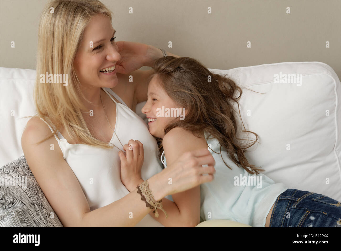 Mère et fille riant sur canapé Banque D'Images