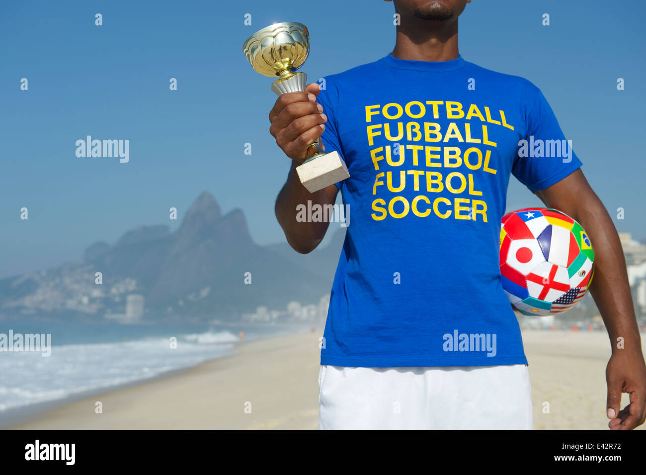 Joueur de football brésilien, Champion holding trophy et ballon de soccer dans le football international t-shirt plage Ipanema Rio de Janeiro Banque D'Images