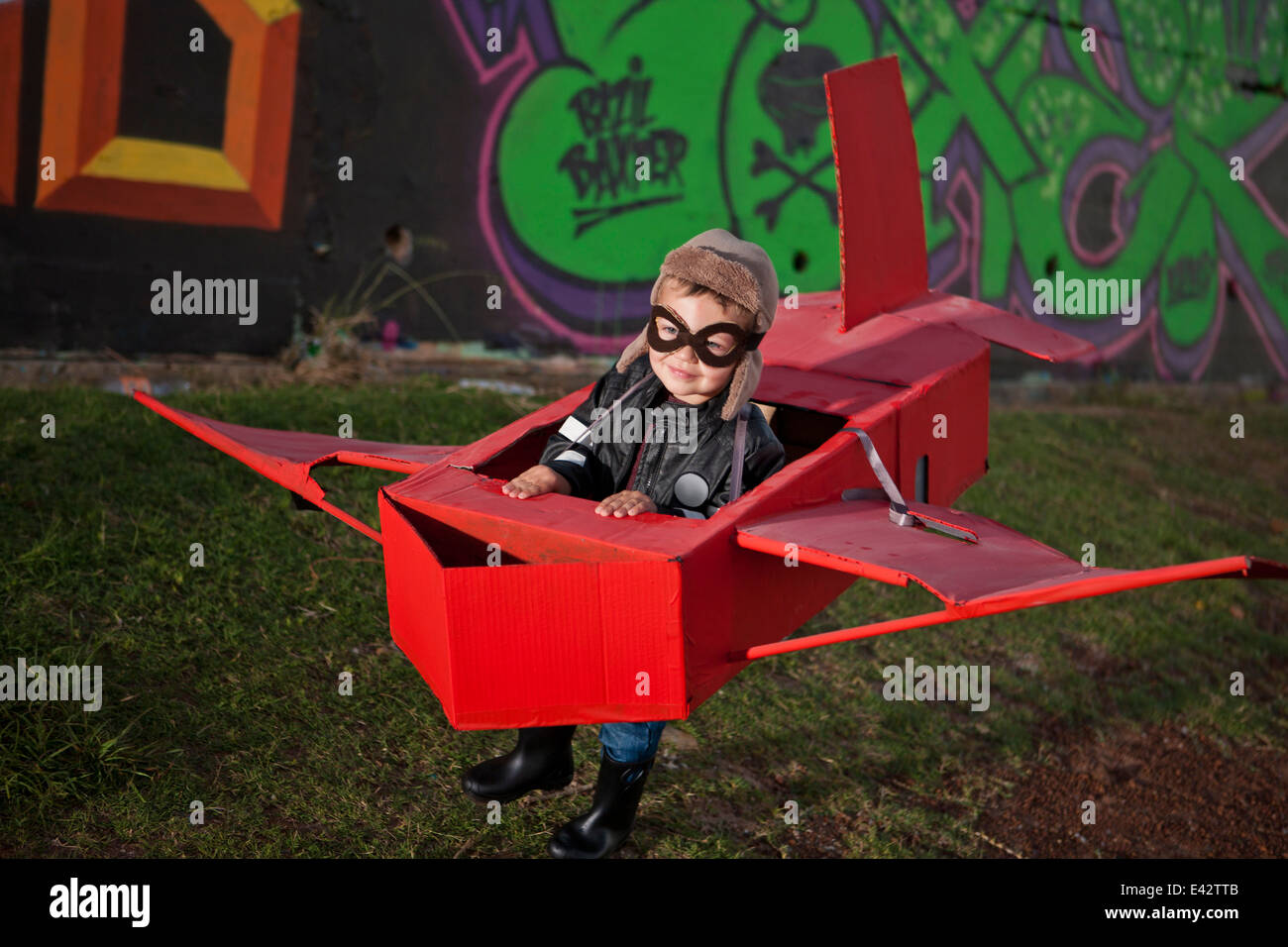 Boy wearing flying nocturne fonctionnant en toy airplane en parc de nuit Banque D'Images