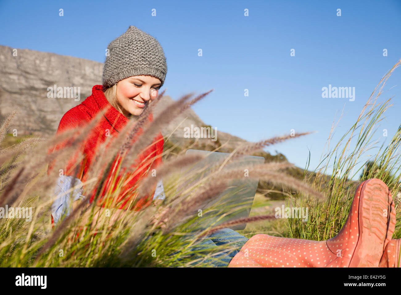 Young woman using laptop in grassy field Banque D'Images