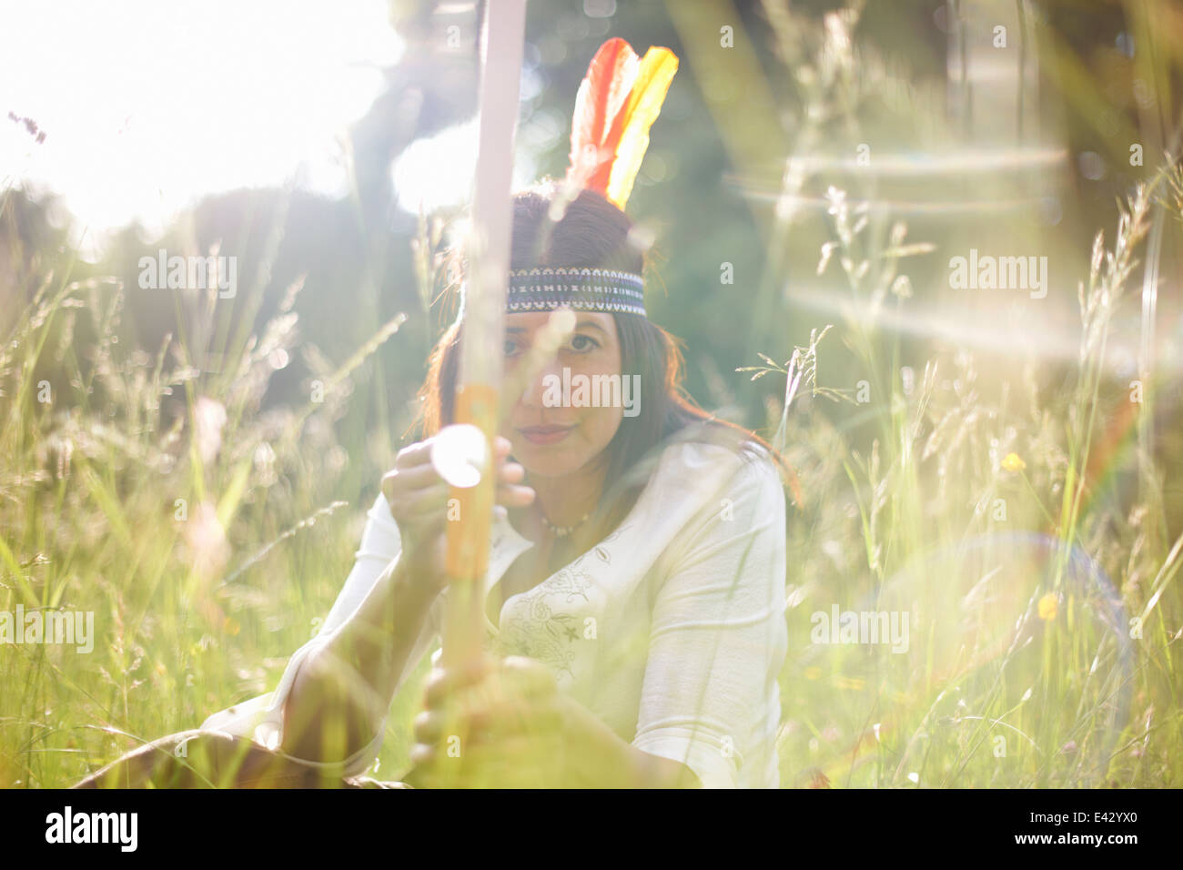 Portrait of young woman holding dans l'herbe haute à l'arc et flèche Banque D'Images