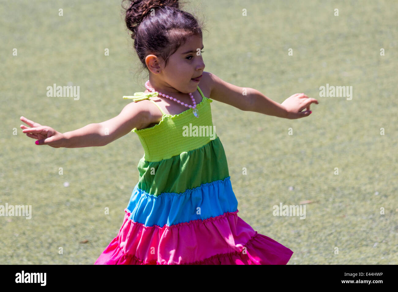 Petite fille danse sur l'herbe avec sa langue qui sort Banque D'Images