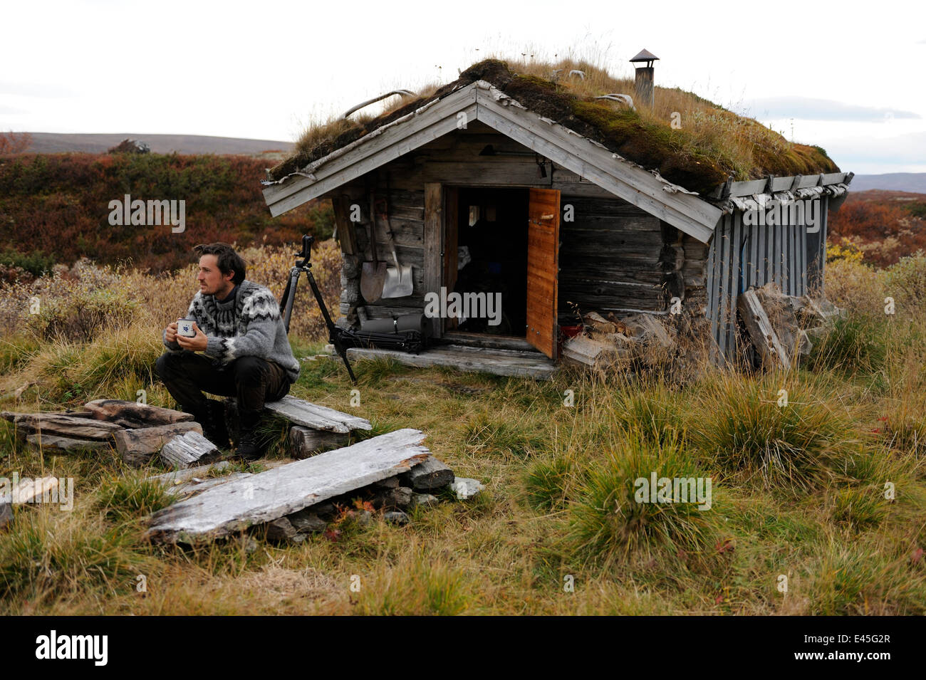 Photographe, Vincent Munier, assis dehors petit toit d'herbe traditionnelle hut, Forollhogna National Park, de la Norvège, sur l'emplacement de Wild Wonders of Europe, septembre 2008 Banque D'Images