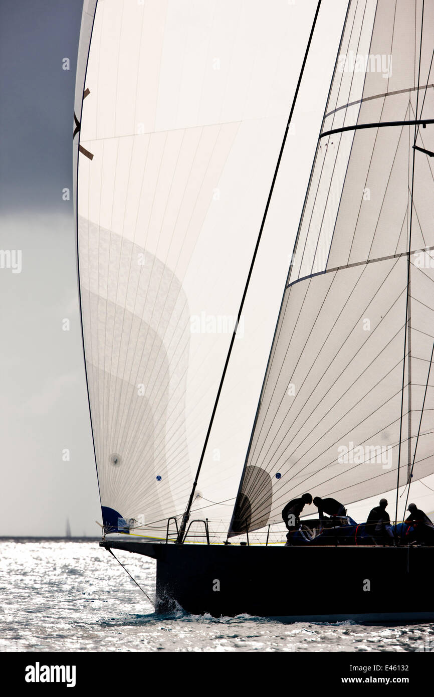 Membre de l'équipage silhouetted against white à bord de spinnaker yacht durant la Heineken Regatta, St Martin, Caraïbes, mars 2011. Banque D'Images