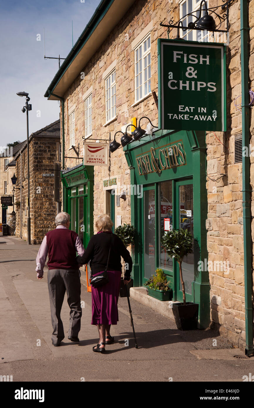 UK, Derbyshire, Peak District, Bakewell, Granby Road, vieux couple centre-ville en passant devant le poisson et chip shop Banque D'Images