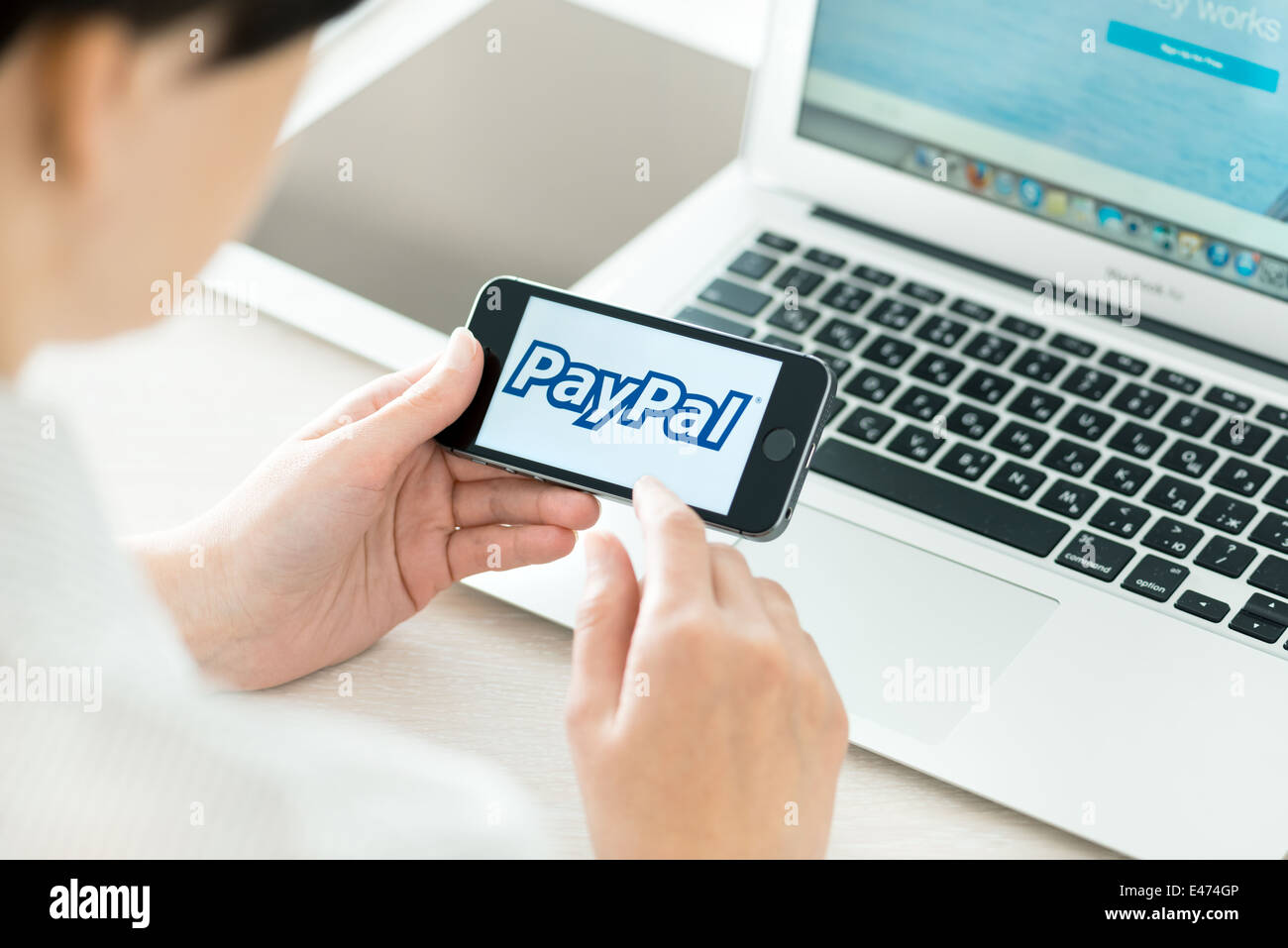 Personne au lieu de travail tenant dans la main un tout nouveau Apple iPhone 5S avec le logo PayPal sur un écran Banque D'Images