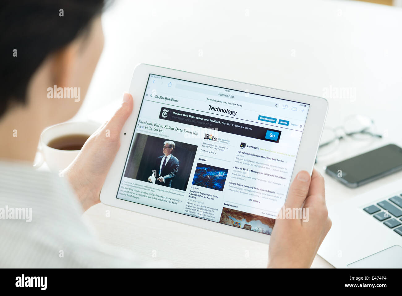Businesswoman reading the New York Times l'article en ligne des nouvelles technologies sur un tout nouvel Apple iPad Air Banque D'Images