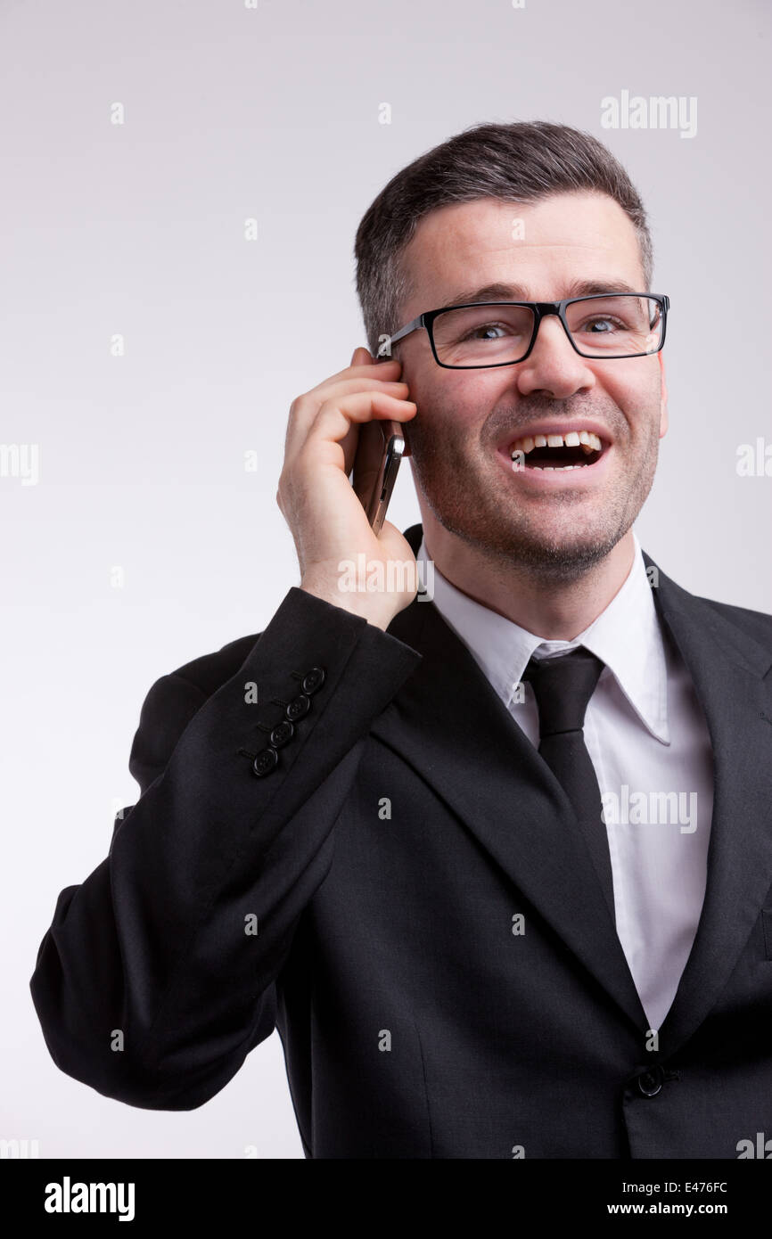 L'homme vêtu d'un élégant avec une paire de lunettes heureux et parle de son téléphone portable Banque D'Images