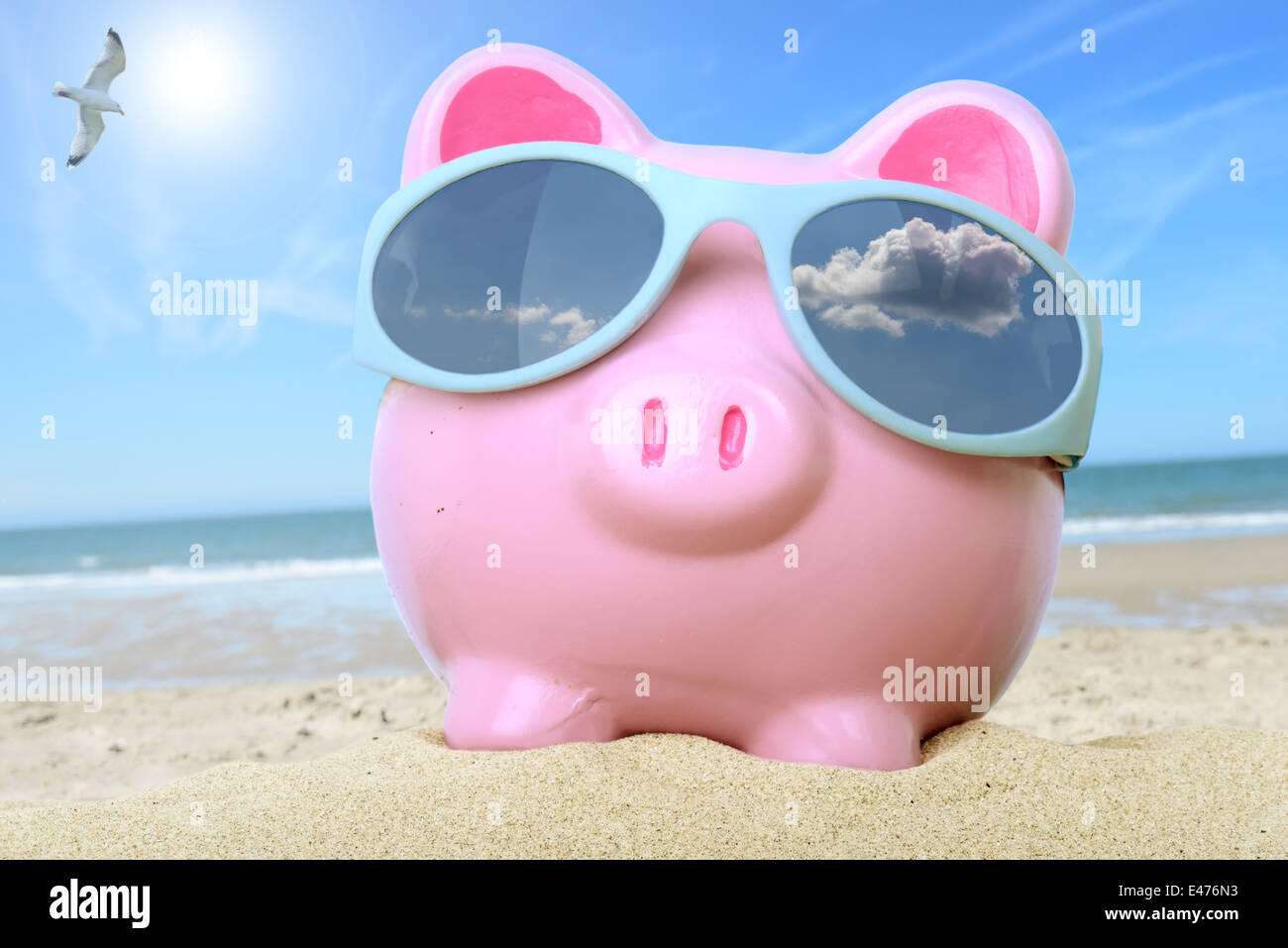 Pink piggy bank sur une plage avec des lunettes Banque D'Images