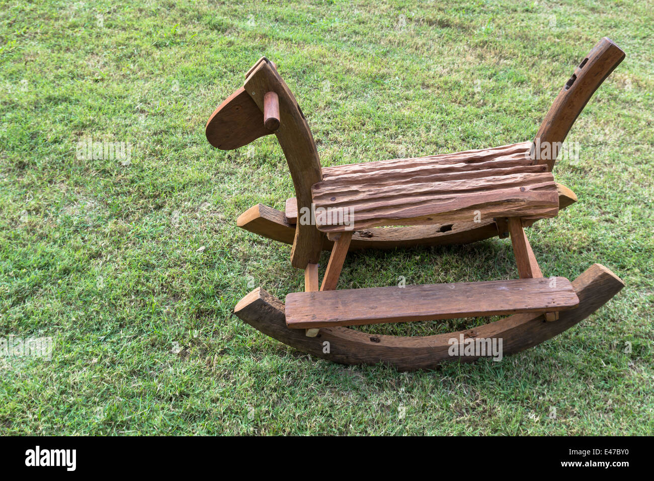 Cheval à bascule en bois sur l'herbe verte. Banque D'Images