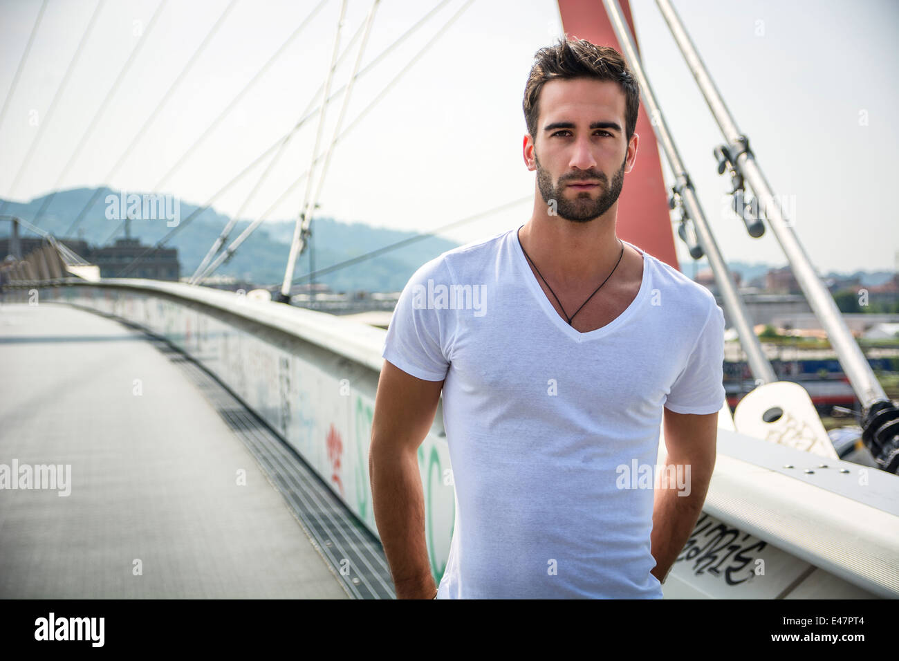 Beau jeune homme barbu à l'extérieur dans l'environnement urbain looking at camera Banque D'Images