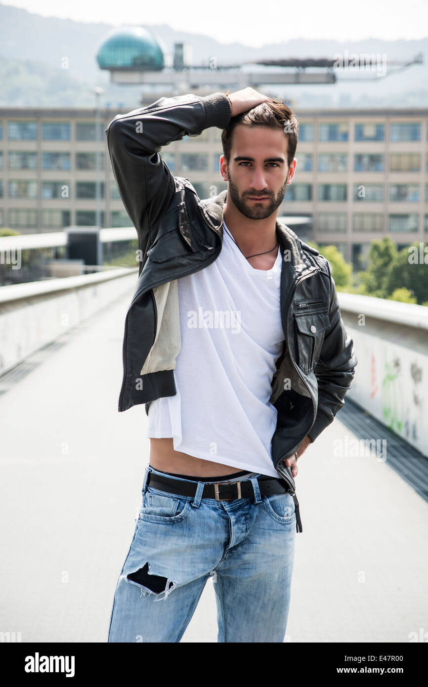 Beau jeune homme barbu à l'extérieur dans l'environnement urbain looking at camera Banque D'Images