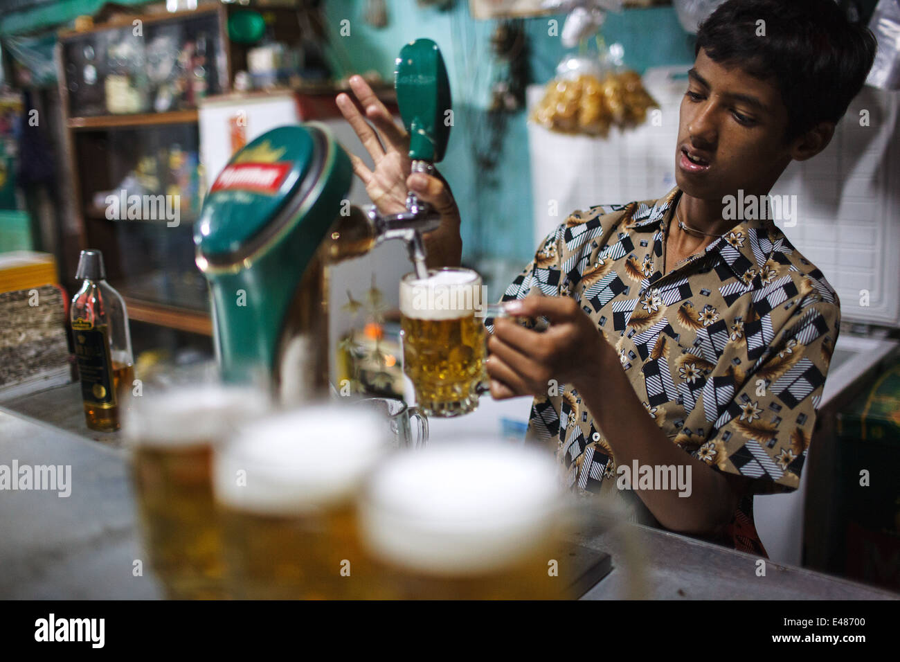 Une jeune personne verse Myanmar Projet de bière dans des verres de bière dans une gare (restaurant, bar) à Bago (Pegu), le Myanmar (Birmanie) Banque D'Images