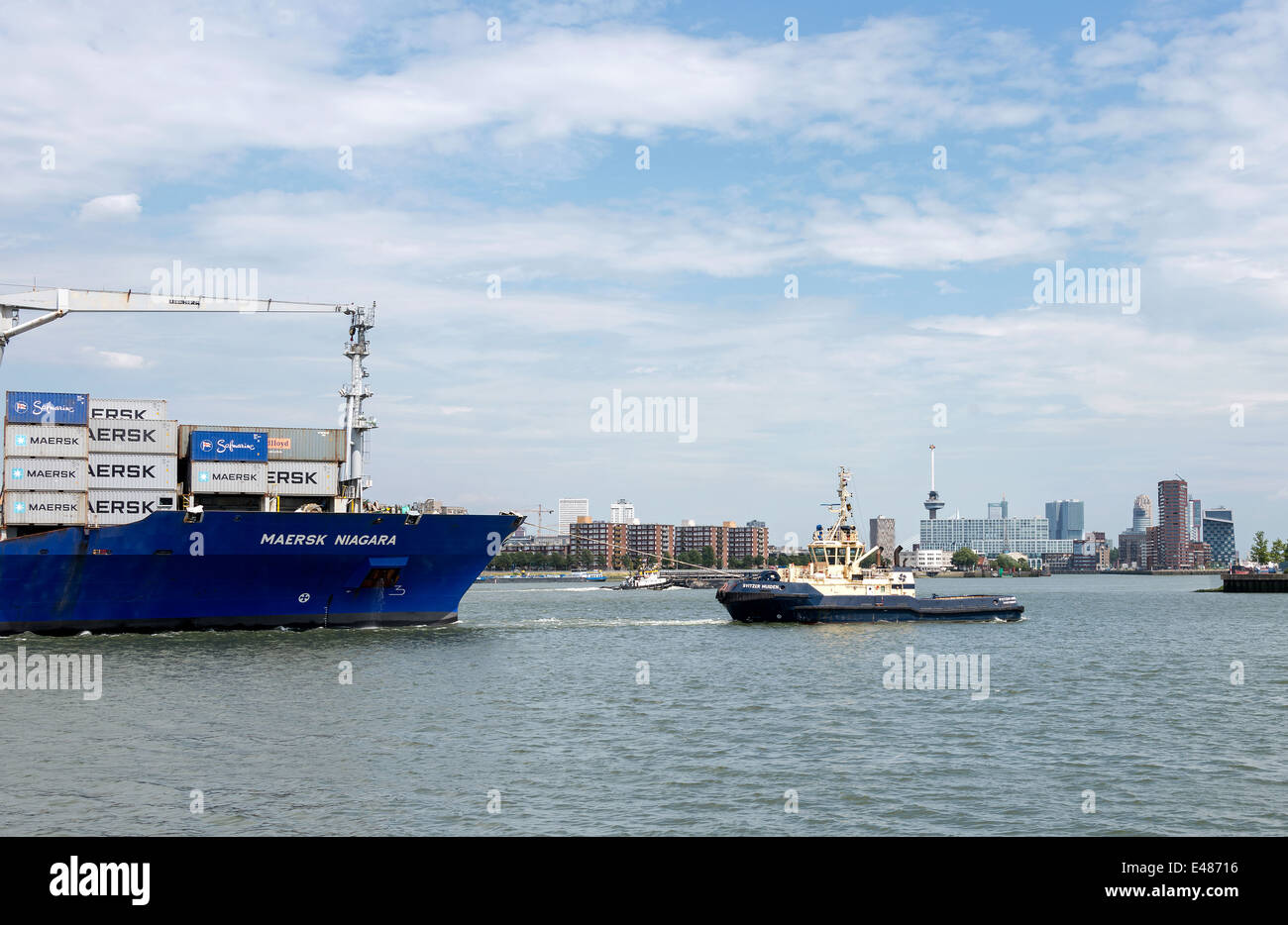 Porte-conteneurs entrant dans le port de Rotterdam avec le remorqueur et skyline en arrière-plan Banque D'Images