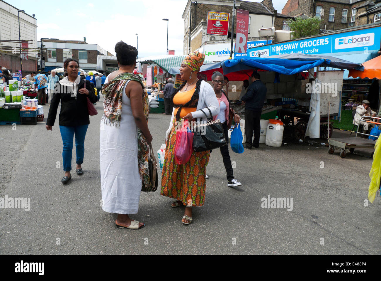 Les femmes afro-britannique shopping dans Ridley Road Market vêtus de la mode africaine ayant une conversation dans l'East End de Londres, Dalston UK KATHY DEWITT Banque D'Images
