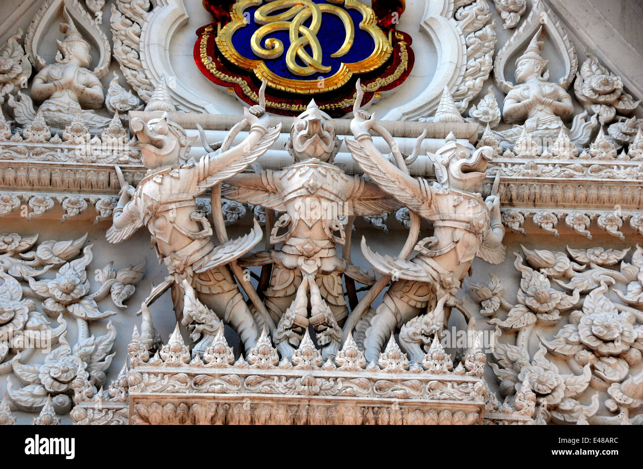 BANGKOK, THAÏLANDE : un trio de figures sculptées Aponsi avec décorations florales et de dragons ornent un tympan du Wat Hua Lamphong Banque D'Images