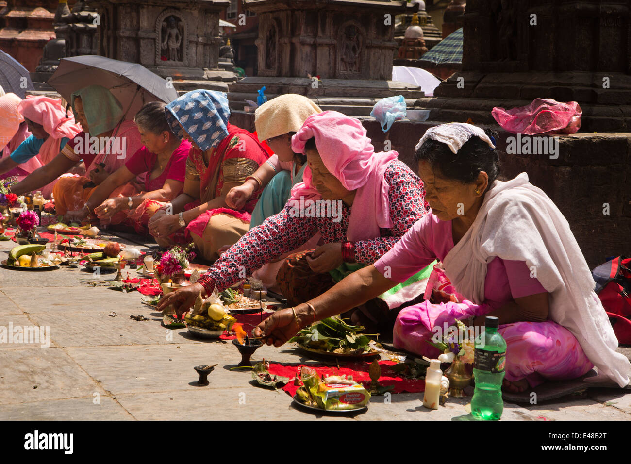 Le Népal, Katmandou, Stupa Kathesimbhu,entreprise de femmes tibétaines bouddhistes rituel puja lampe d'éclairage Banque D'Images