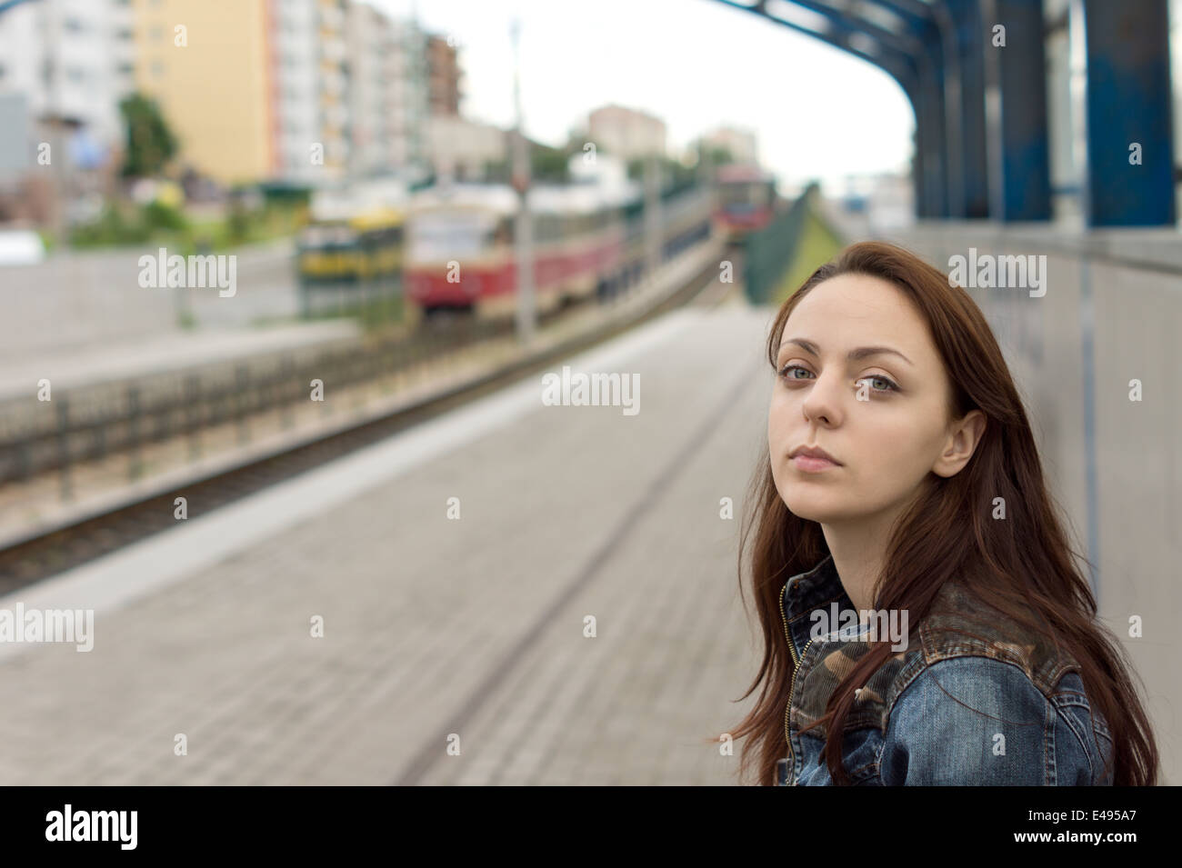 Belle jeune femme aux cheveux rouges avec une expression du visage triste seul d'attente sur la plate-forme d'une gare Banque D'Images