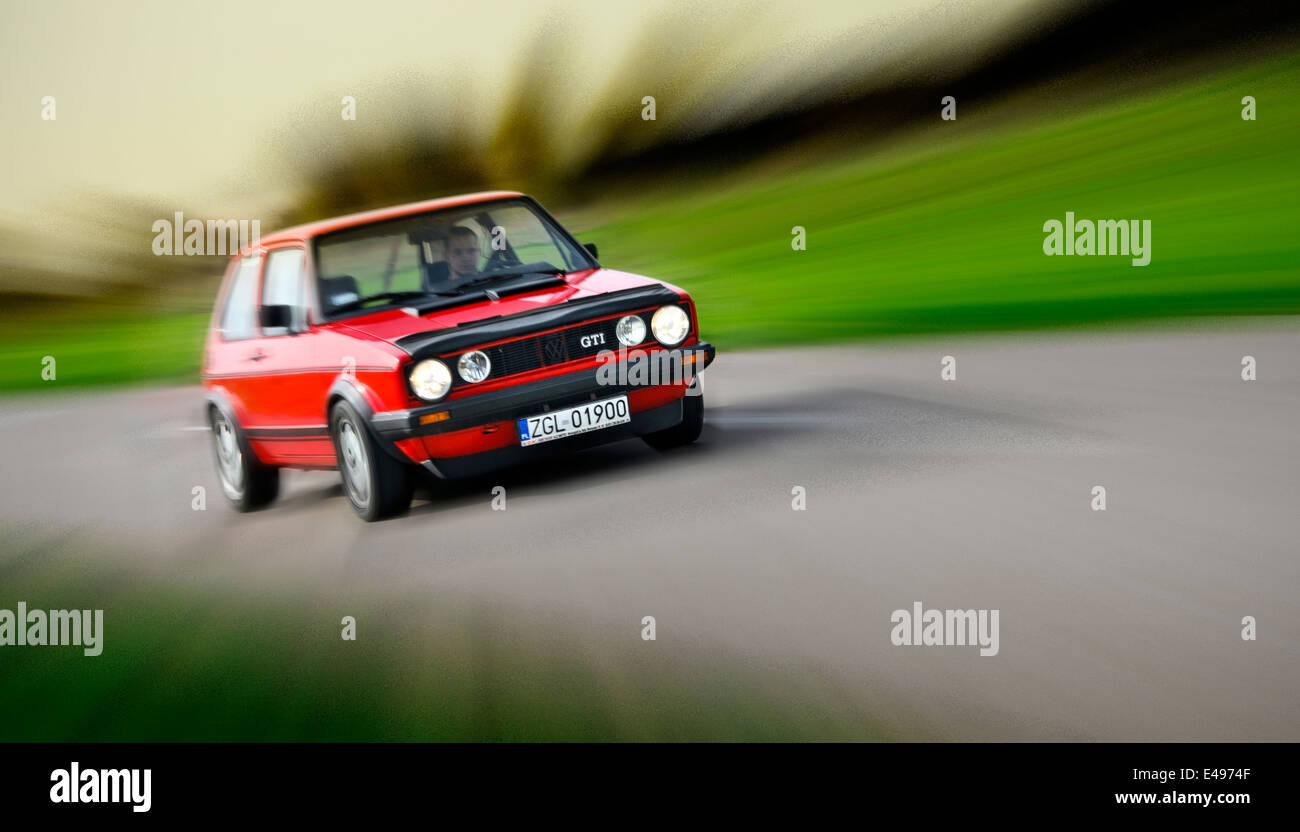 VW Golf GTI rouge tournant sur la route Banque D'Images