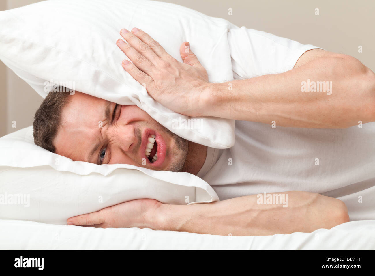 Portrait of young woman in bed en colère sur le bruit Banque D'Images
