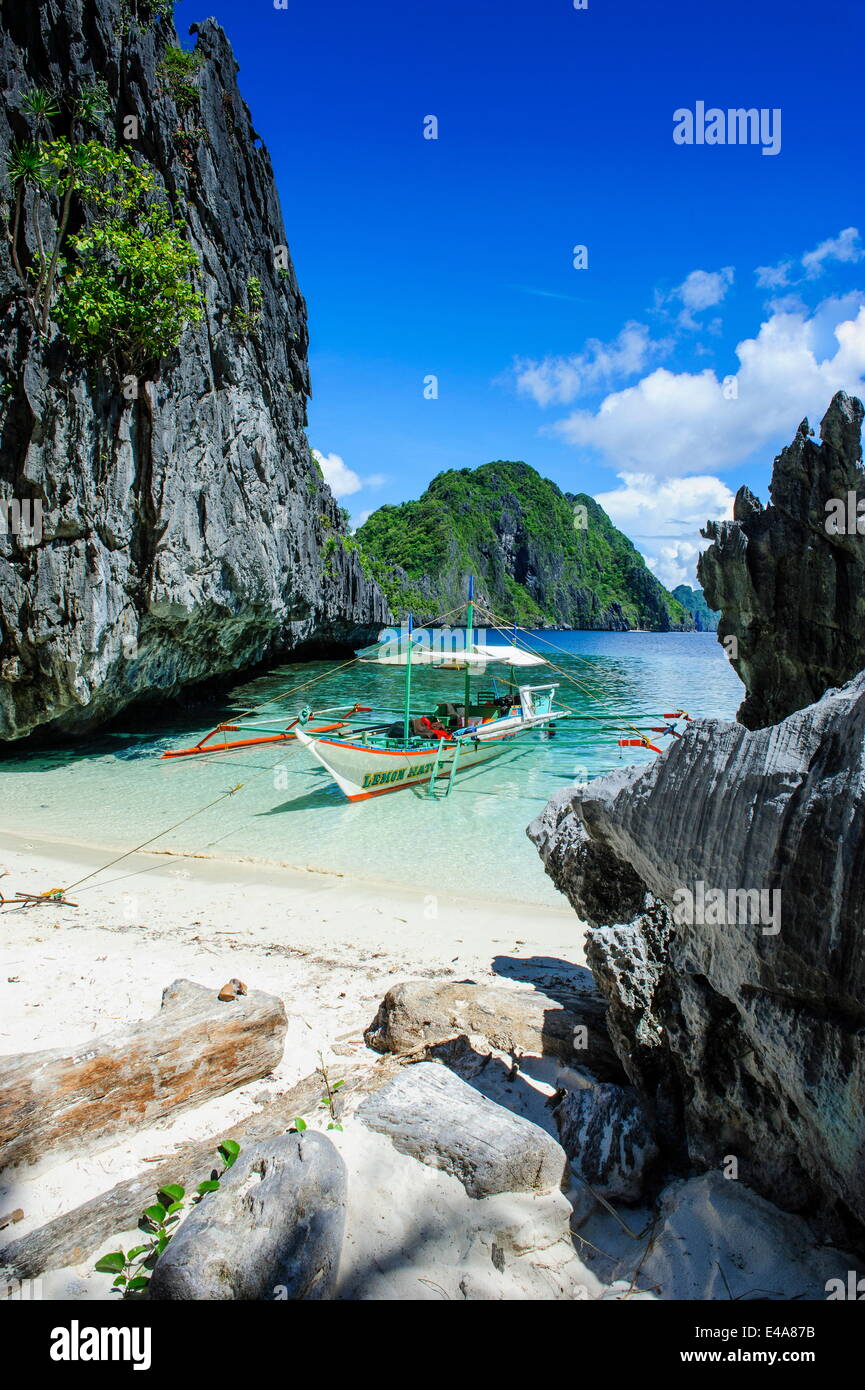 Outrigger bateau sur une petite plage de sable blanc et ses eaux claires dans l'archipel de Bacuit, Palawan, Philippines, Asie du sud-est Banque D'Images