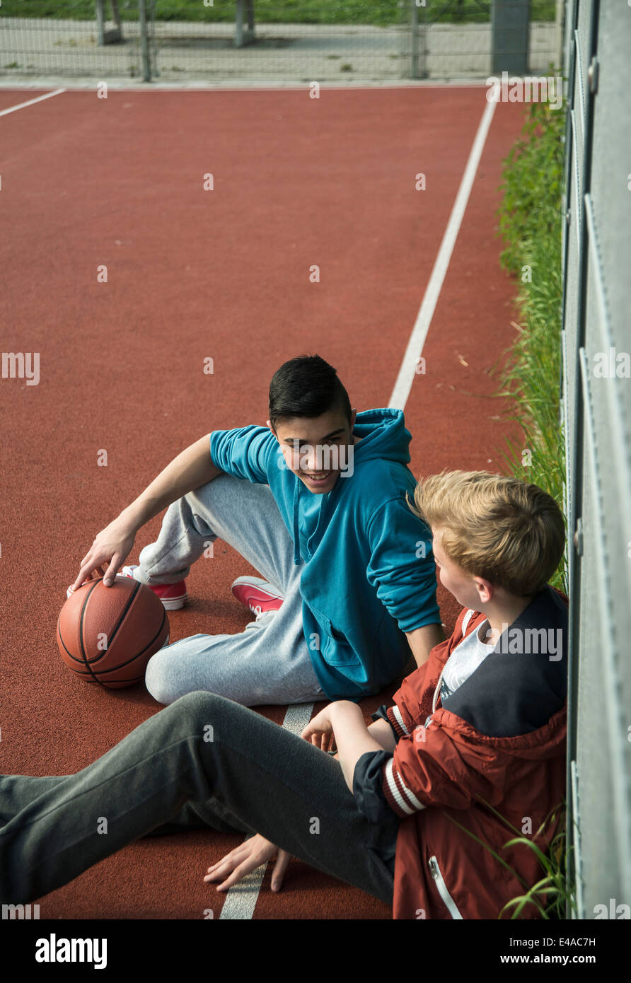 Deux garçons de basket-ball avec leanaing contre fence Banque D'Images