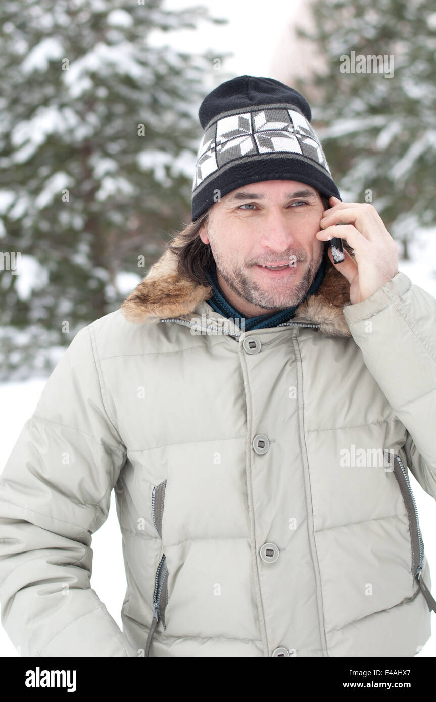 Un homme parle de la neige d'hiver téléphone mobile cellulaire moyen-âge 40 45 cap hat jacket spruce pine forest park sapins frosty gel com Banque D'Images