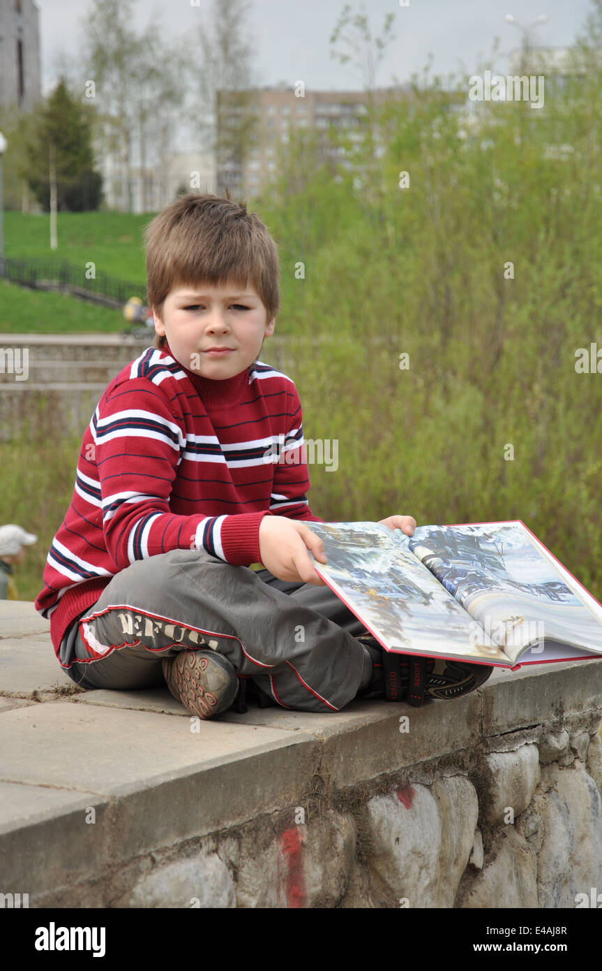 Un garçon avec un livre dans city park Banque D'Images