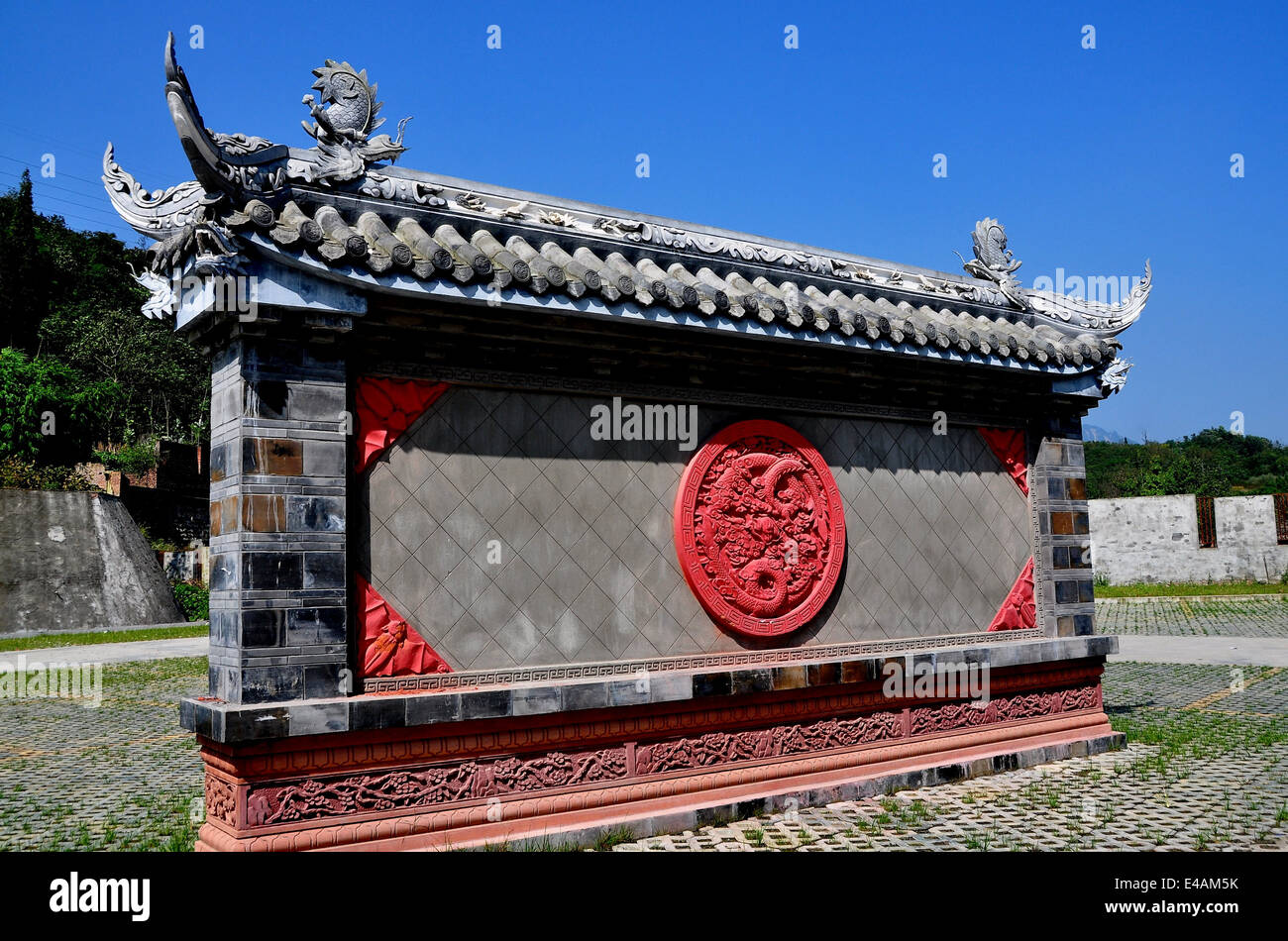 XING XING VILLE, Chine : un mur de cérémonie avec disque dragon dragon et chiffres de toit Banque D'Images