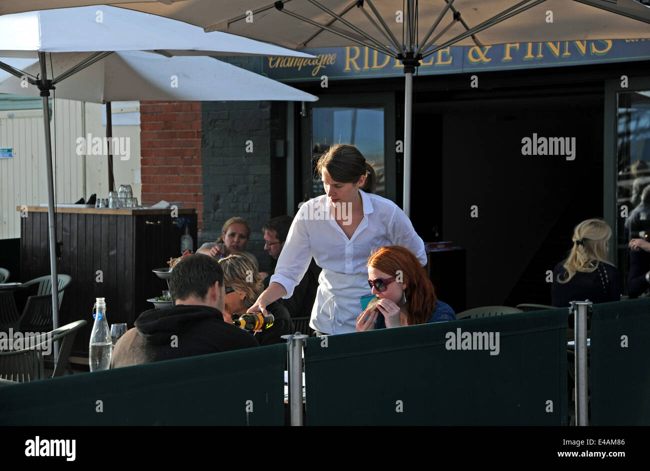 Serveuse servant du vin aux clients assis à l'extérieur au restaurant Riddle & Finns sur la plage de Brighton en front de mer UK 2014 maintenant appelé due South Banque D'Images