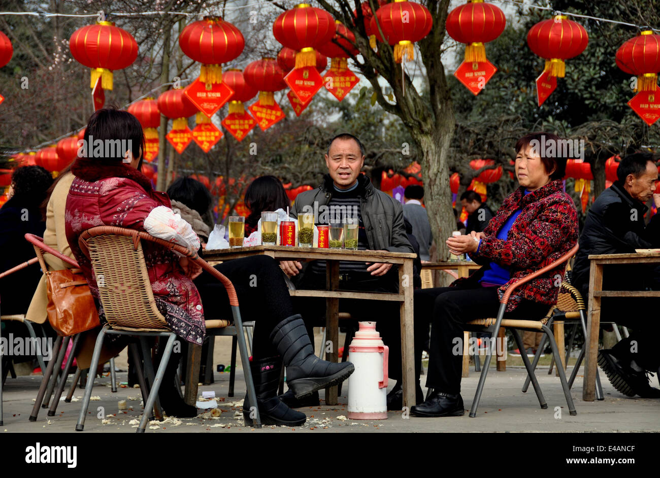Pengzhou, Chine : Famille à Pengzhou Park assis à une table en bois boire le thé sous une mer de rouge lanternes du Nouvel An chinois Banque D'Images