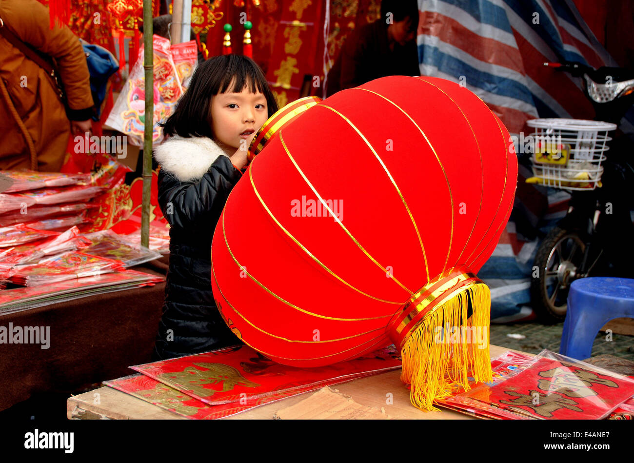 Pengzhou, Chine : Chinese girl holding Red Lantern Nouvel An chinois à un fournisseur. stand à la place du marché de plein air à long Xing Banque D'Images