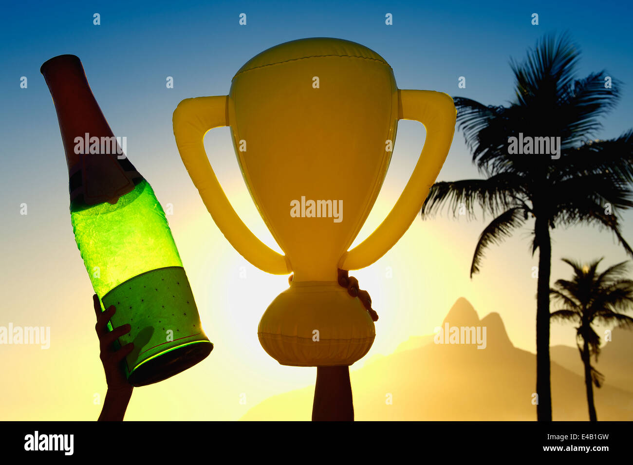 Célébrer hands holding inflatable trophée et bouteille de champagne au coucher du soleil au-dessus des toits de Rio de Janeiro Brésil Banque D'Images